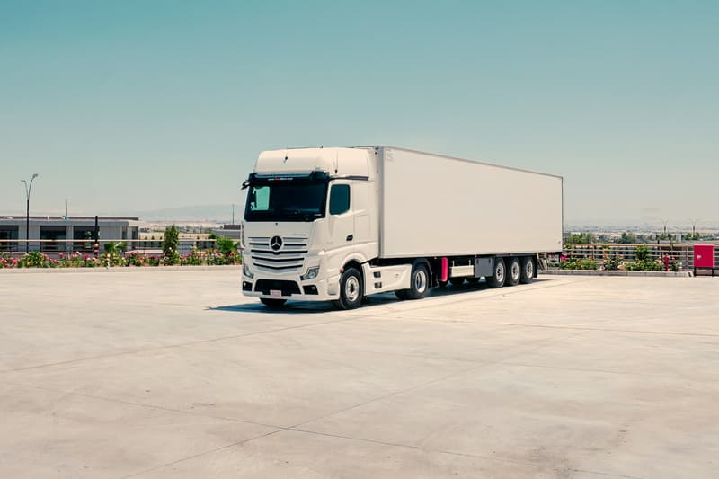 Vit lastbil med skåpsläp parkerad på en ljus betongplan